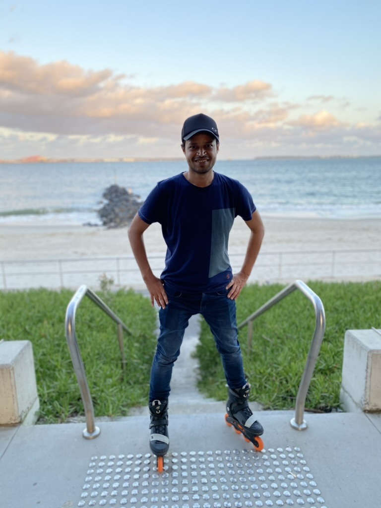 Faiz standing on inline skates beside the ocean
